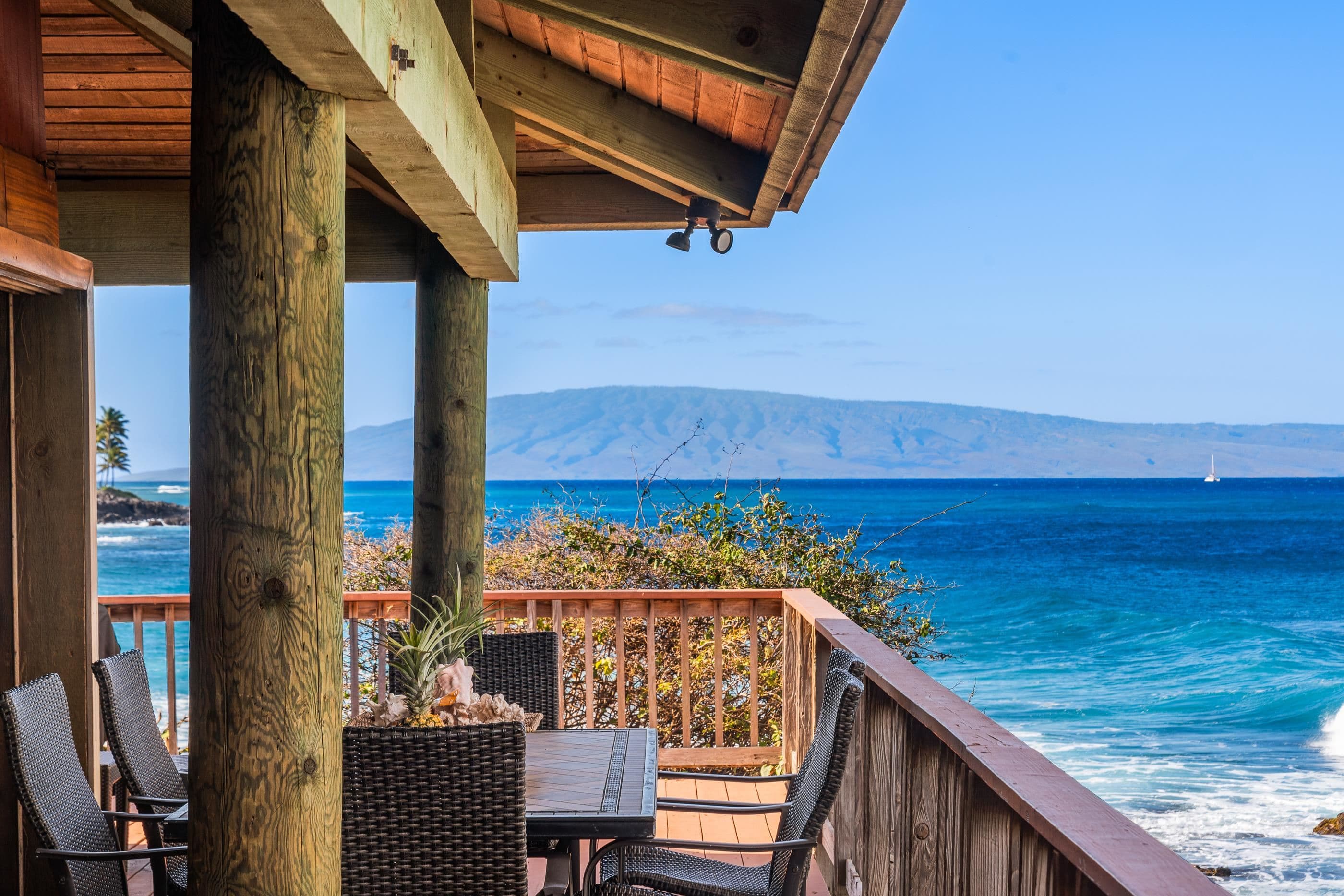 A quiet corner of the covered deck, table and chairs above the rocks with the island in the distance