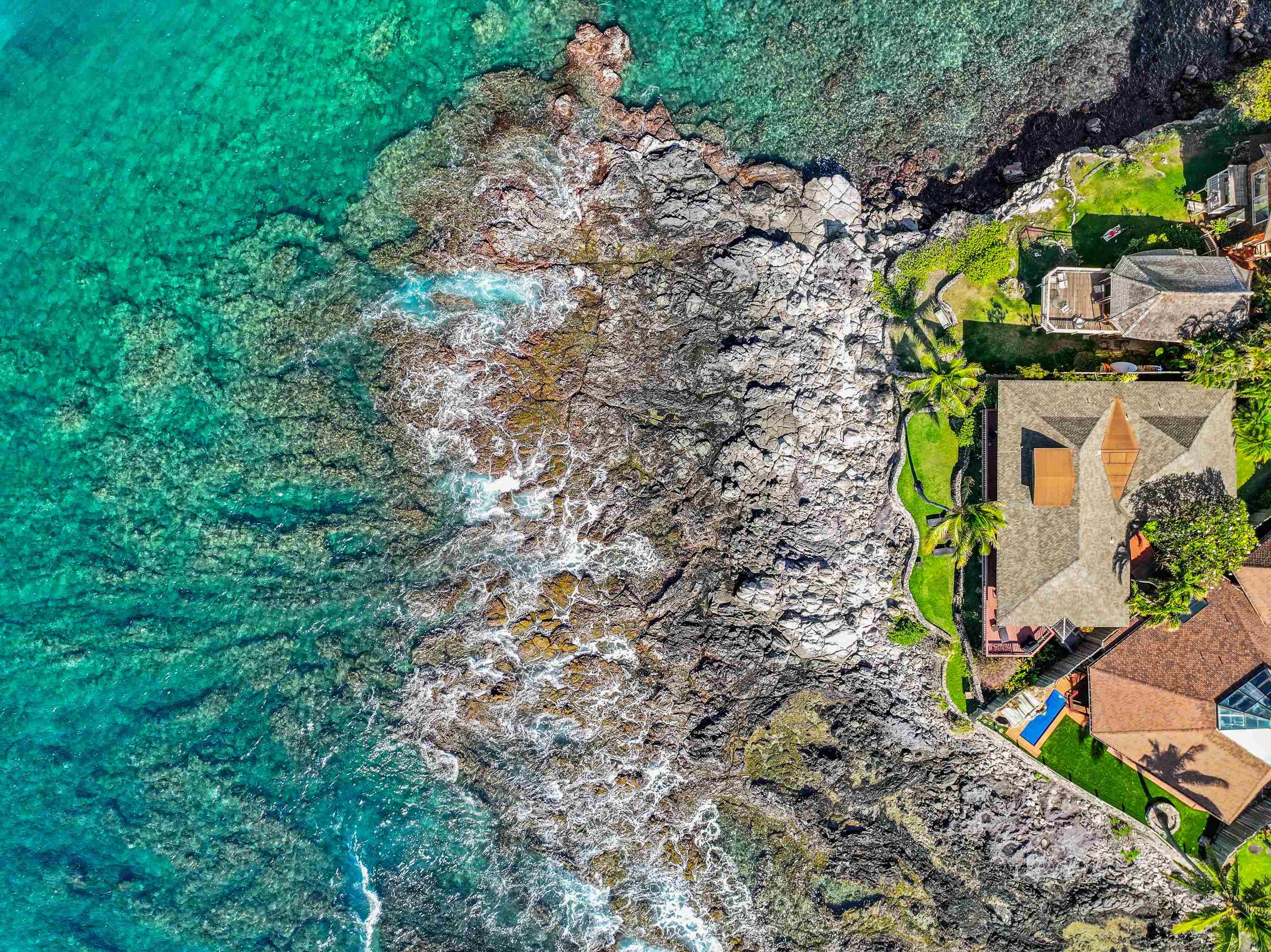 Top-down aerial of the lava point and the turquoise reef wrapping the property